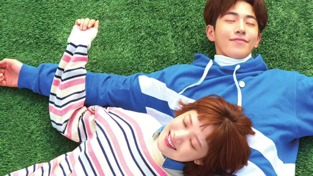 Os atletas universitários Kim Bok-joo e Jung Joon-hyung sorrindo em uma pista de atletismo.