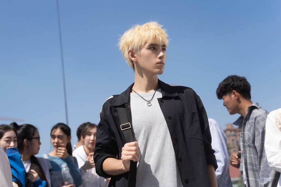 Li Xun com seu icônico cabelo loiro platinado, olhando fixamente para Zhu Yun.