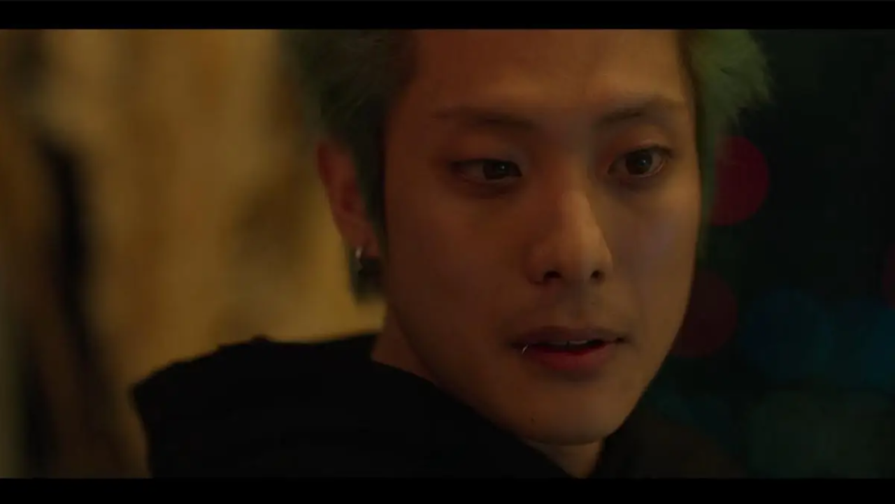 Lee Myeong Ro como Allen, sentado em frente a computadores, com expressão cínica e arrogante.