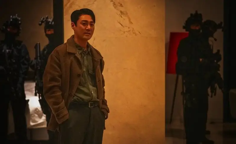 Choi Young Joon como Min Gang Yong, com curativos no rosto, sendo atendido por médicos.