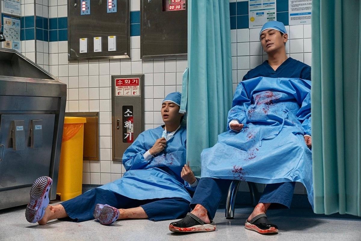 Dois médicos em uniformes cirúrgicos realizando um procedimento de emergência.