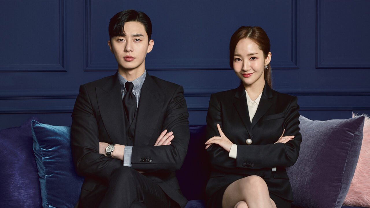 O vice-presidente Lee Young-joon e a secretária Kim Mi-so caminhando lado a lado em trajes sociais.