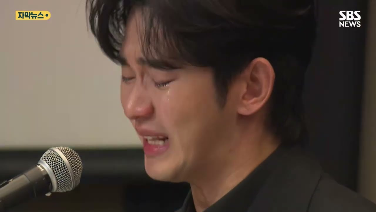 Kim Soo-hyun falando ao microfone em coletiva de imprensa com expressão séria.
