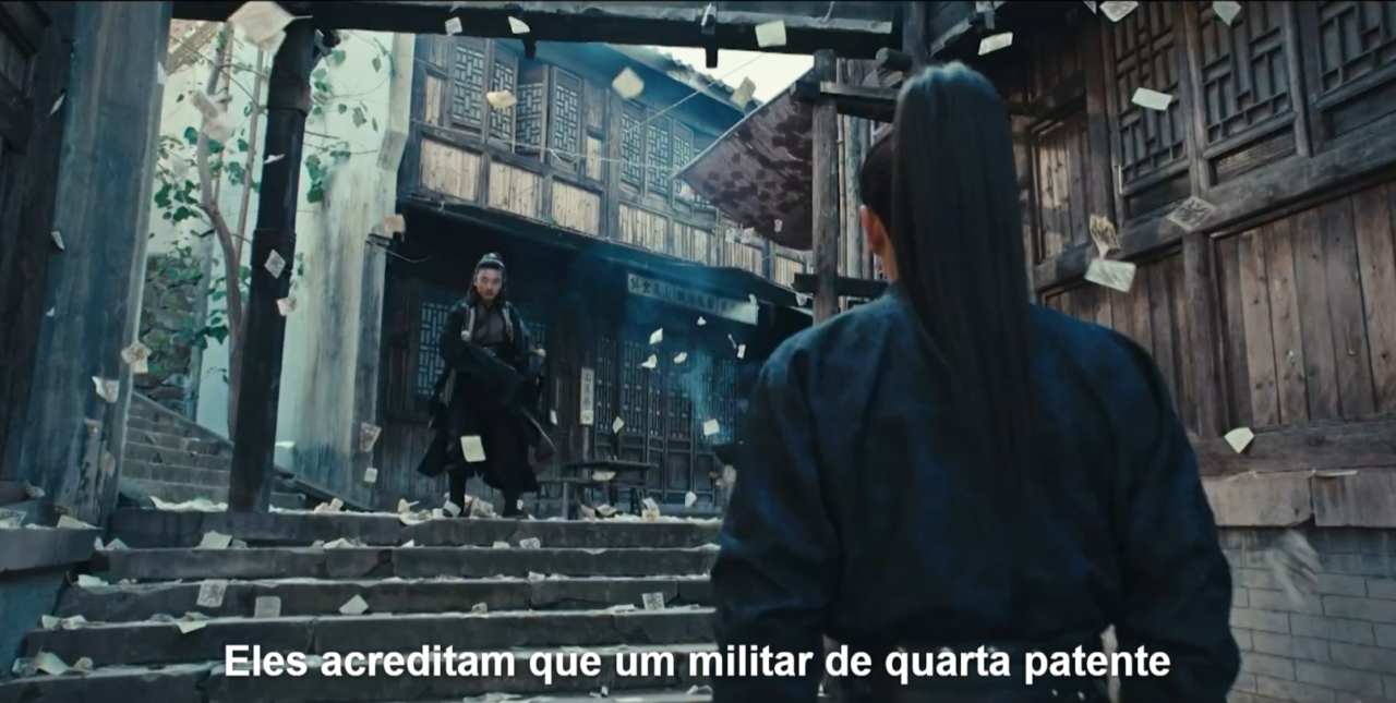 Beco estreito com paredes de pedra e iluminação alaranjada de lanternas, com várias pessoas em trajes tradicionais chineses e um personagem de capa preta se misturando à multidão.