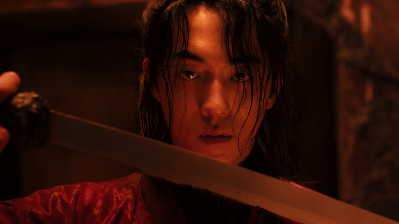 O ator Nam Joo-hyuk no papel do caçador de fantasmas Gu-cheon, entrando em um lago escuro com uma corda no pescoço e galhos de pêssego nas costas em cena da série A Leste do Palácio