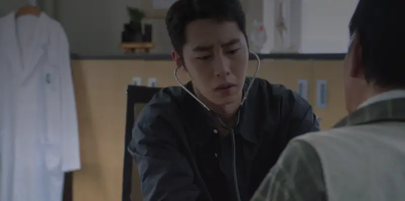 Médico sul-coreano atendendo um paciente em uma maca modesta.