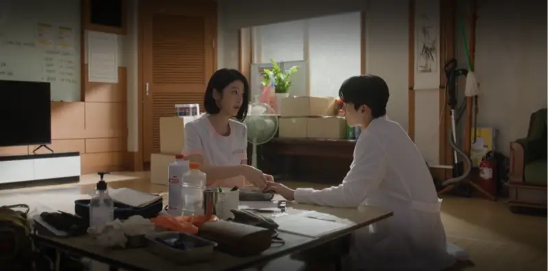 Ator sul-coreano com expressão cansada e reflexiva vestido com jaleco médico.