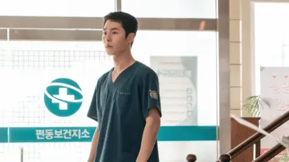O ator Lee Jae Wook caracterizado como o médico Do Ji Ui, com expressão de desgaste em um ambiente hospitalar na ilha de Pyeongdong-do.