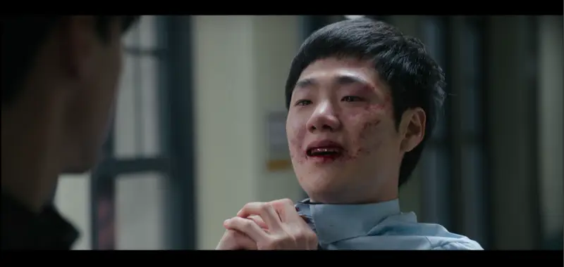 Jovem sul-coreano com feição arrogante nos corredores de uma escola.