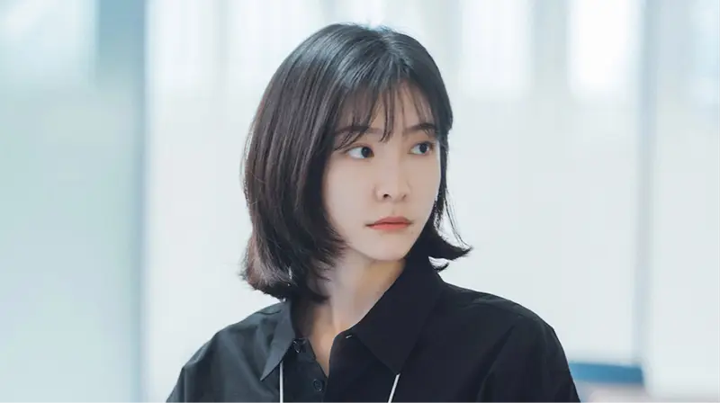 Atriz sul-coreana observando um relógio com expressão de cansaço.