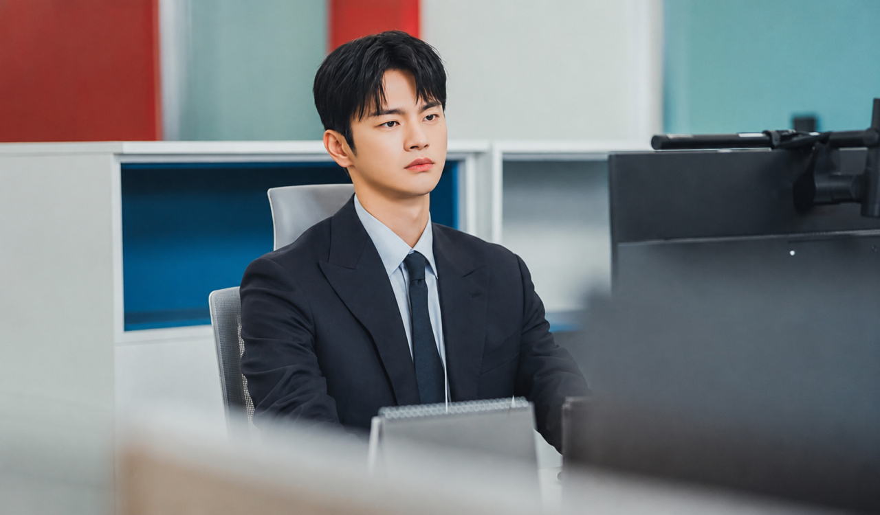 O personagem Kang Si Woo em sua mesa de trabalho na Saeum Electronics, isolado dos demais funcionários da sala.
