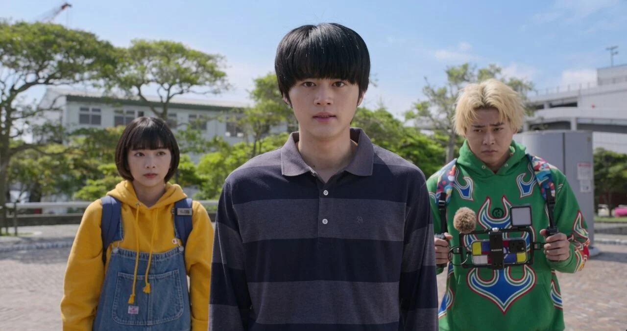Ator japonês jovem com expressão séria e roupas casuais.