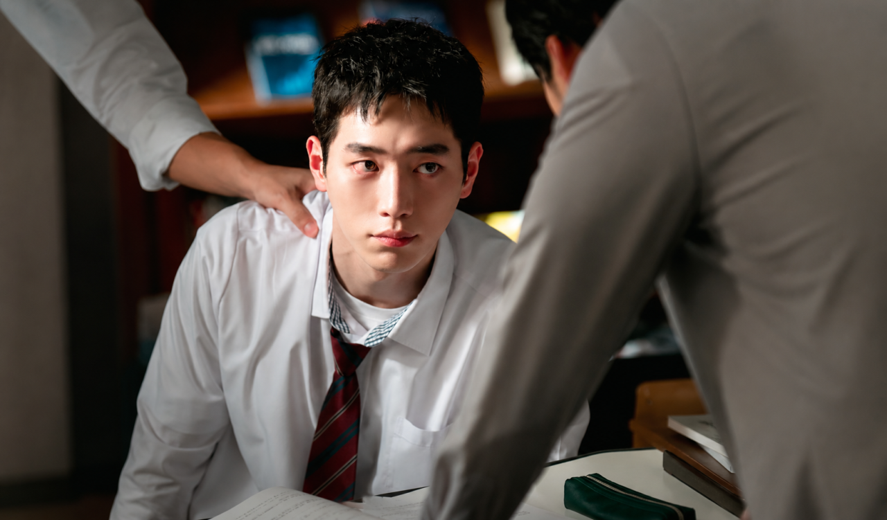 Ator sul-coreano adulto vestindo uniforme colegial com expressão observadora.