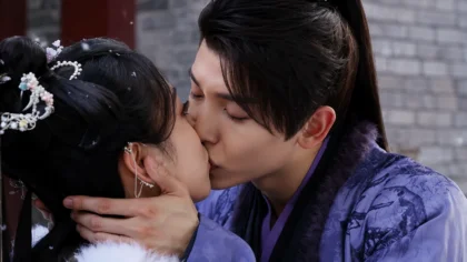Fan Yun e Qi Zheng se olhando no pátio coberto de neve, momentos antes de se abraçarem no final de A Lenda das Nuvens Rosadas.