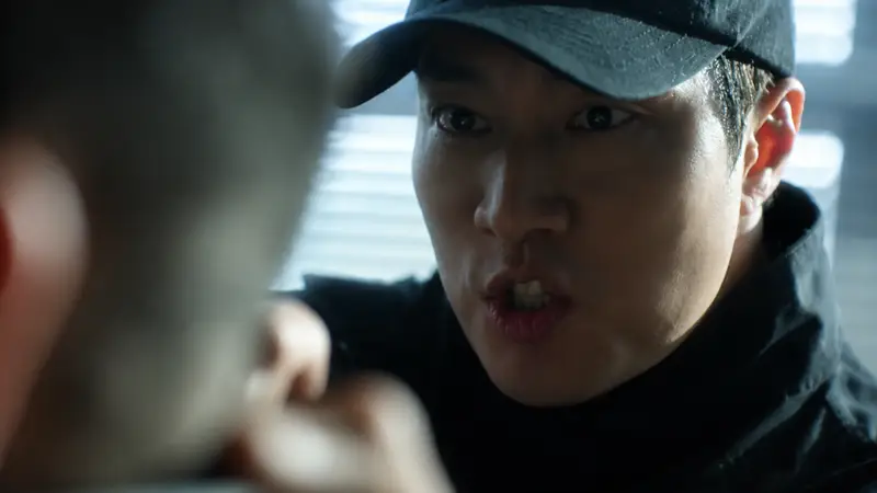 So Ji Sub caracterizado como o protagonista de Agente Kim, segurando uma arma em um cenário urbano.