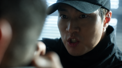 So Ji Sub caracterizado como o protagonista de Agente Kim, segurando uma arma em um cenário urbano.