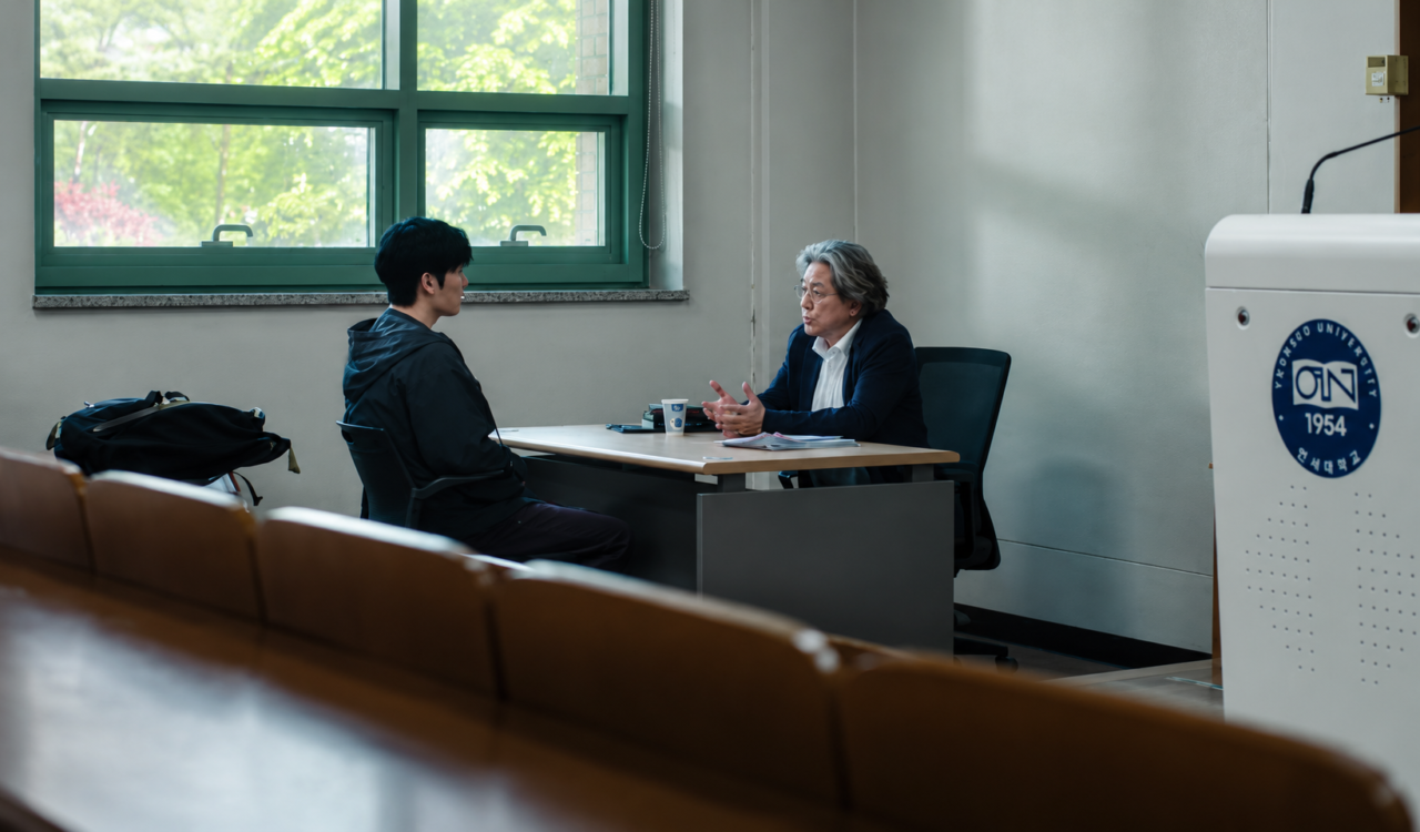 Lee Kang entregando um manuscrito para Heo Mun Oh, momento que marca o início da dependência psicológica do professor na trama.