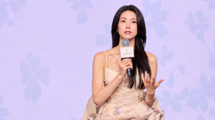 Atriz Ha Young durante evento da Netflix com um microfone nas mãos.