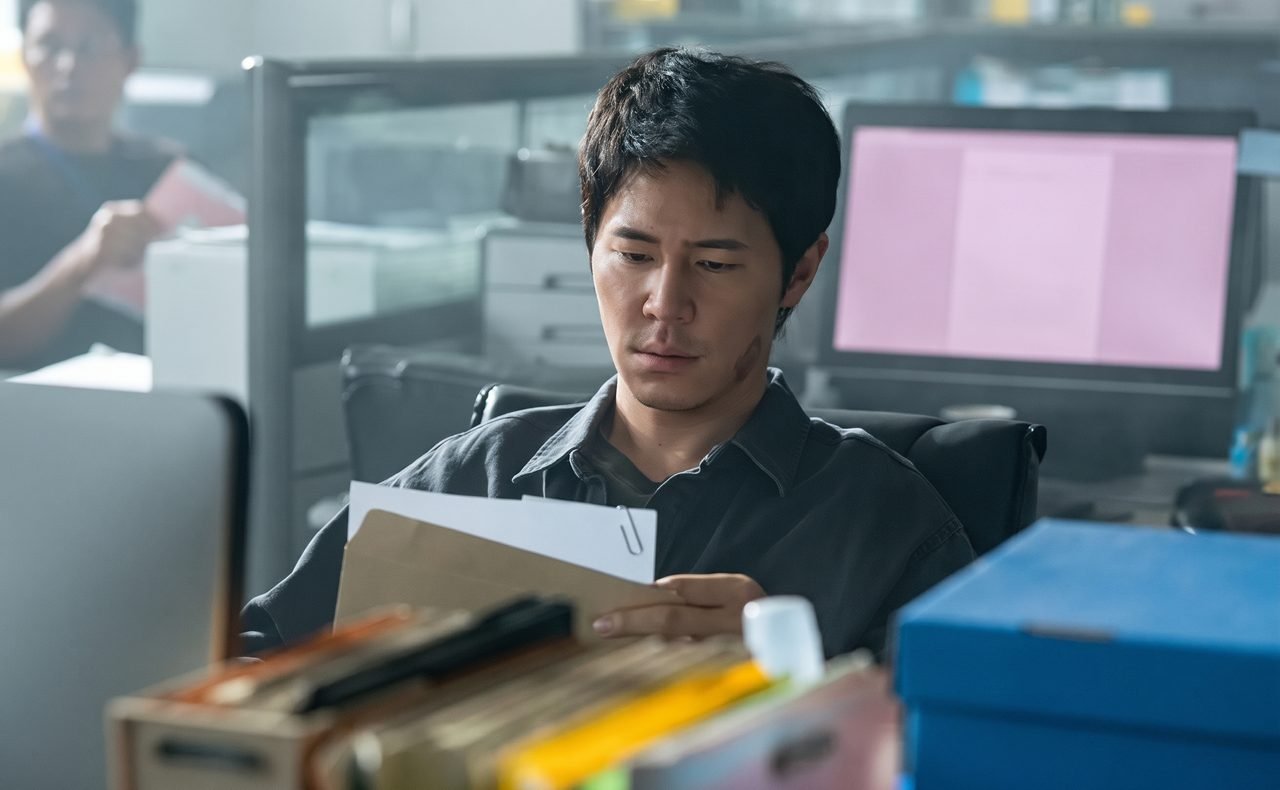 O ator Lee Kyu Hyung caracterizado como detetive em ambiente urbano.